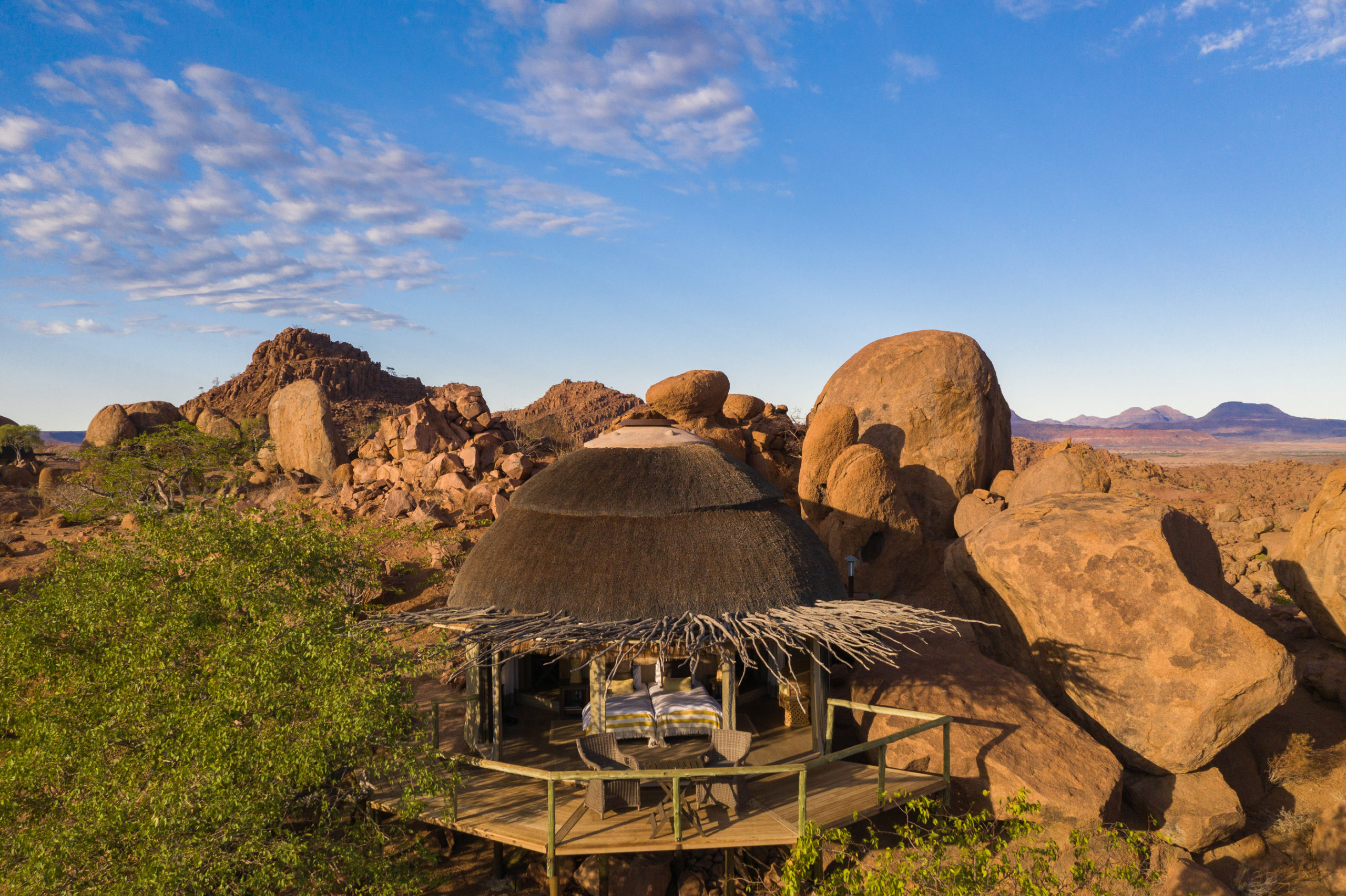 A thatched Mowani suite tucked between giant ochre boulders, its deck and private plunge pool catching the last light of Damaraland.