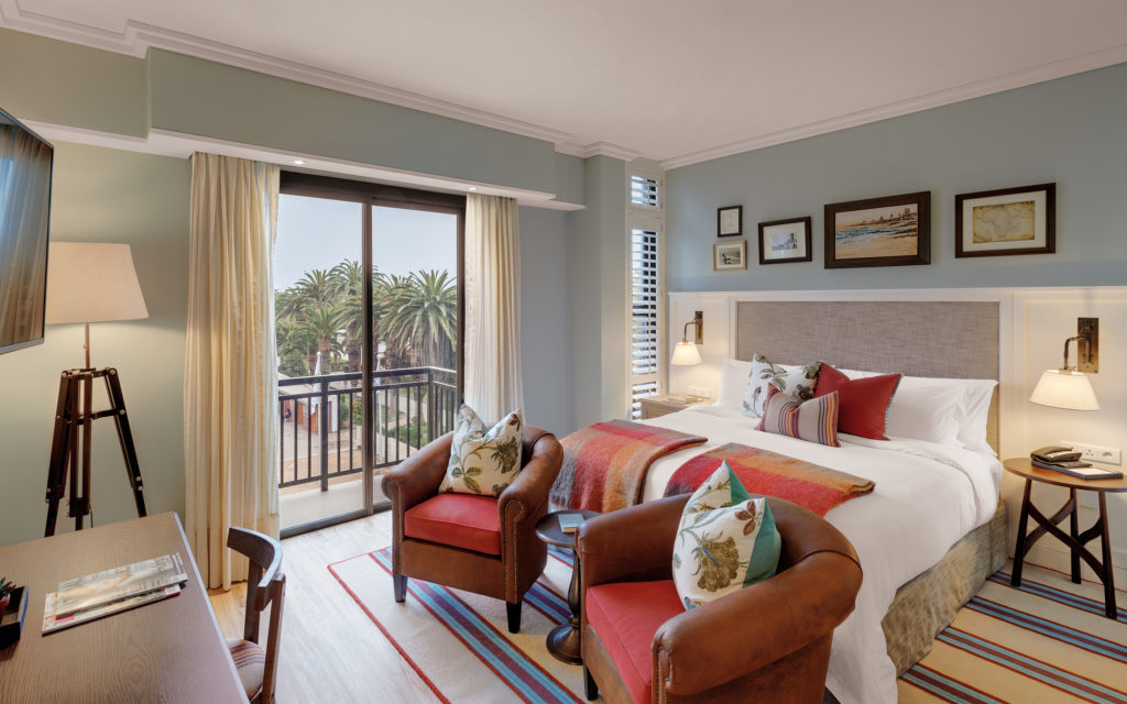 Luxury Room at Strand Hotel Swakopmund with a private balcony overlooking palm trees and the Swakopmund coastline
