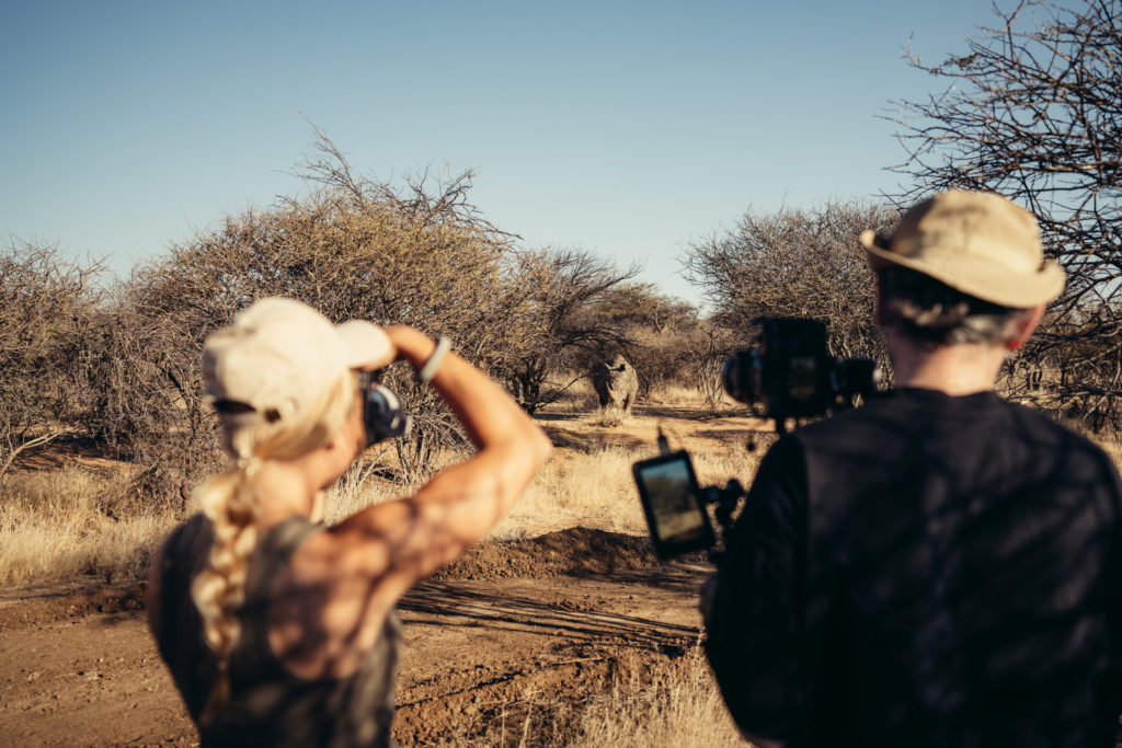 Guests photographing a white rhino during a guided bush walk at Okonjima