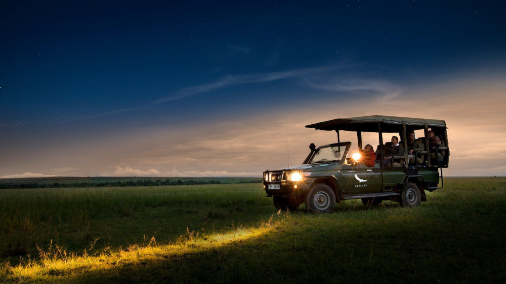A game-viewing vehicle pauses on the plains at dusk during a night drive from Bateleur Camp in the Masai Mara