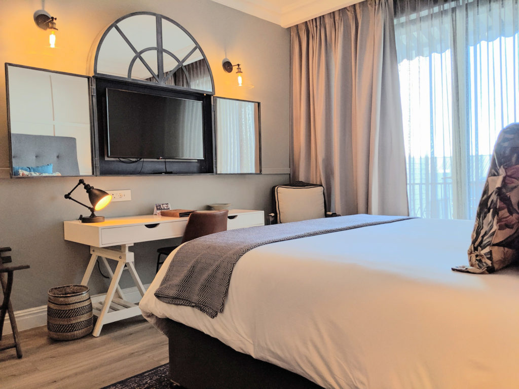 Double room at The Weinberg with arched mirror, wall-mounted TV and writing desk beside floor-to-ceiling windows