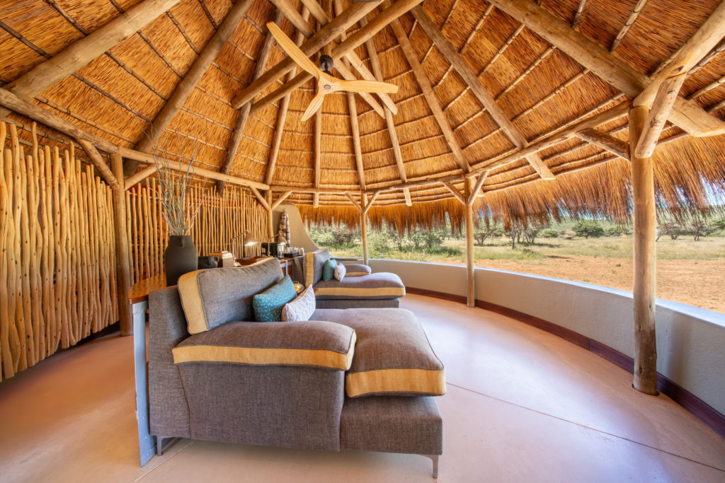 Thatched sala at Okonjima Luxury Bush Camp with loungers overlooking the bush