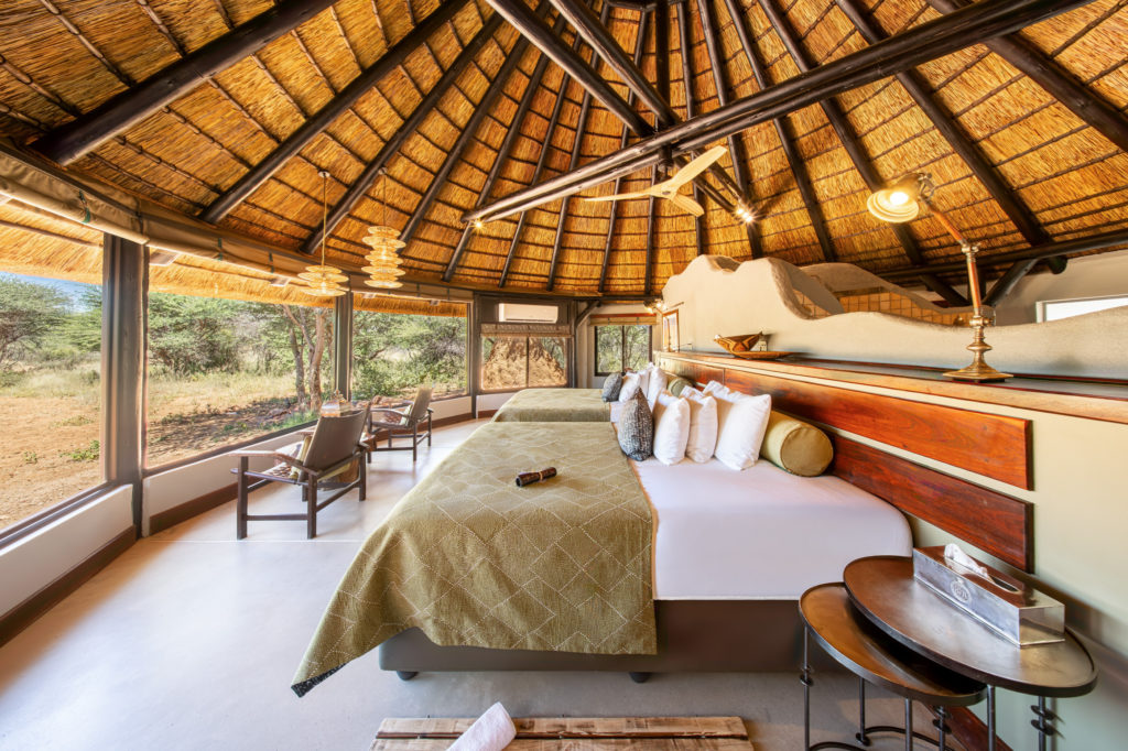 Chalet interior at Okonjima Luxury Bush Camp with twin beds and reserve views