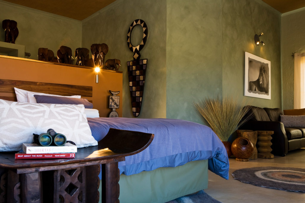 Chalet interior at Okonjima Luxury Bush Camp with African carved décor and views over the reserve
