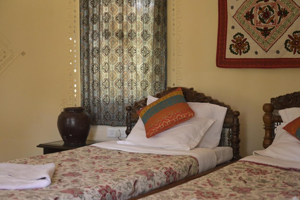 Carved wooden headboard with cushions against a lippan mirror-work wall