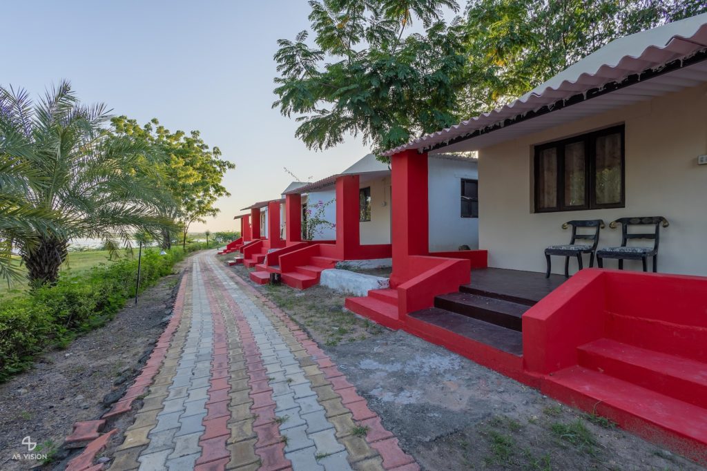 Cottage porches with red steps along a paved garden path, Kutch Safari Resort