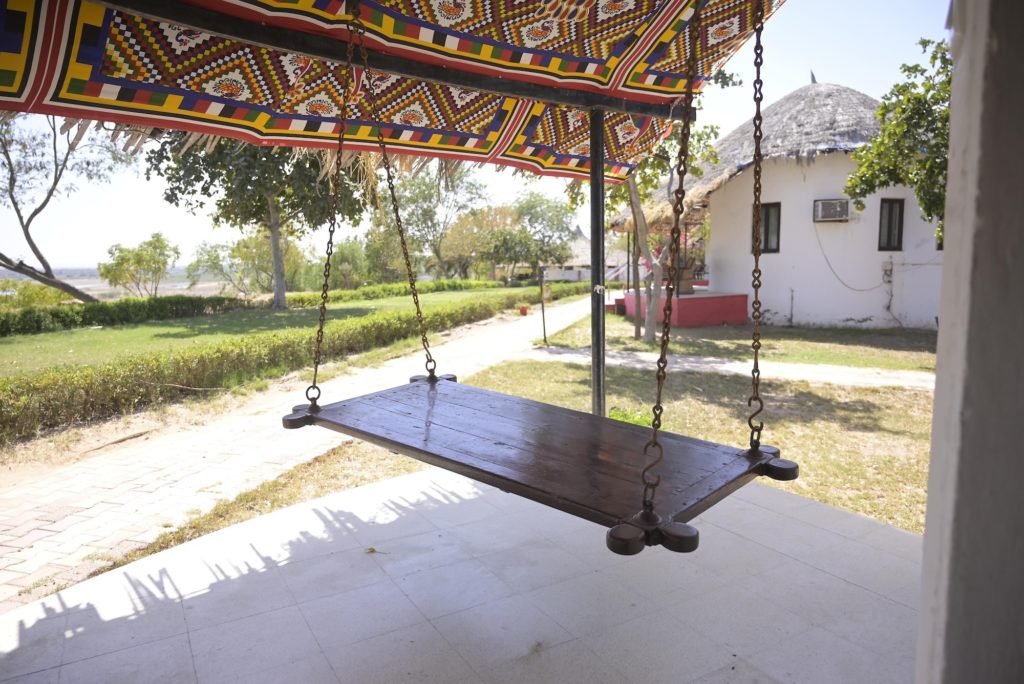 Traditional wooden jhula swing on a cottage porch overlooking the lawn