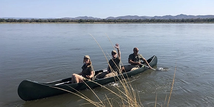 Travellers paddling in a canoe on the Zambezi River with their guide at Kutali Camp.