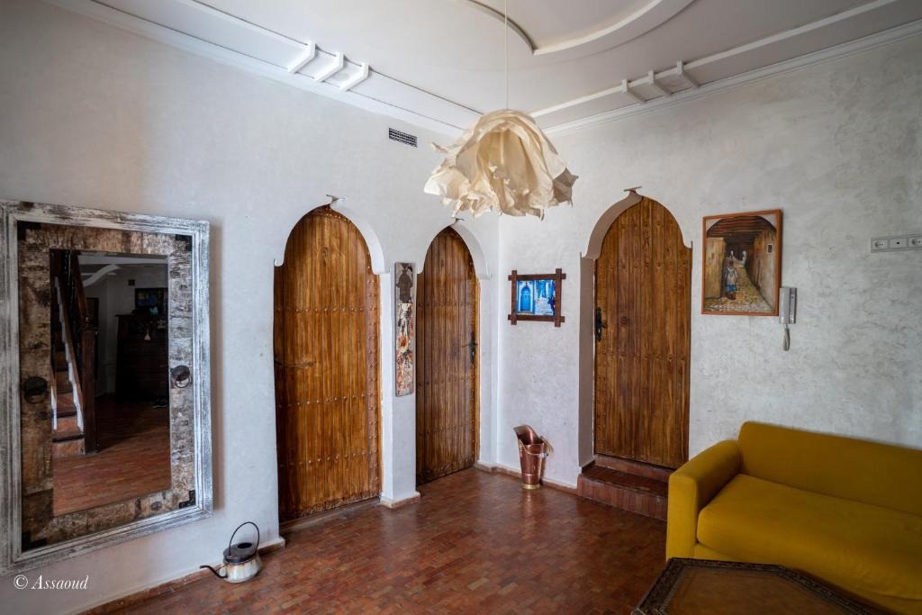 Entrance hall with arched wooden doors, a gilt-framed mirror and a mustard velvet sofa