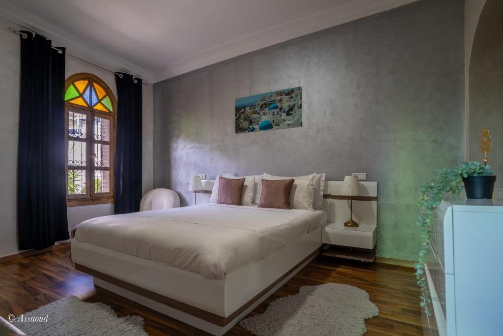 Bedroom with grey textured walls, a stained-glass arched window and a low platform bed