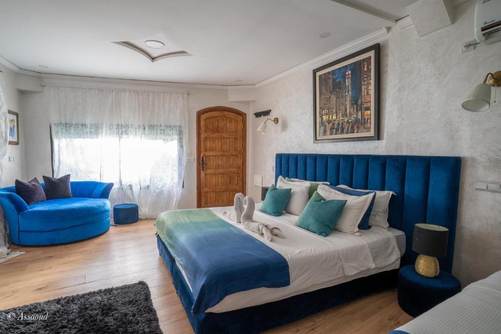 Suite with a deep blue upholstered headboard, curved velvet sofa and framed cityscape artwork