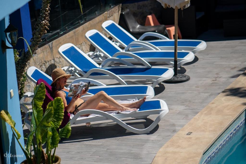 Guest relaxing poolside on a sun lounger beneath the hotel's blue façade