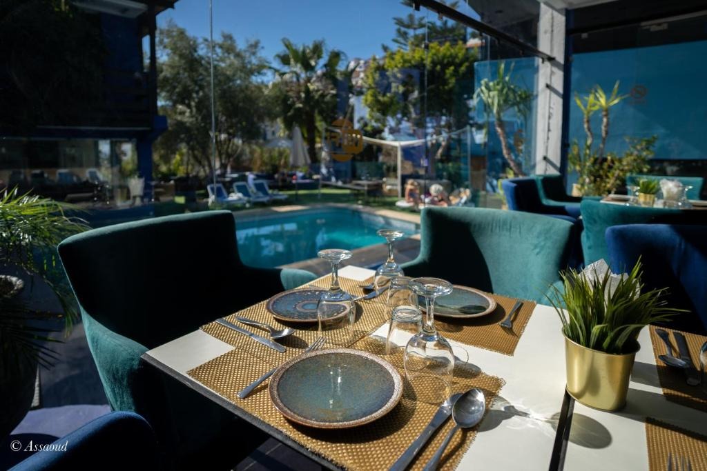 Restaurant seating in teal velvet chairs beside the pool, with mountains visible in the distance