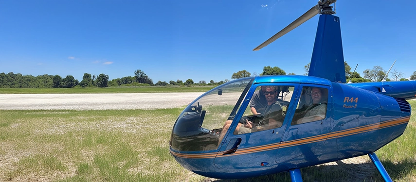 Guests smile from inside a light helicopter, ready for a scenic flight that reveals the sweeping wetlands and islands surrounding Karangoma.