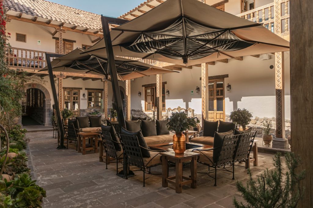 The colonial courtyard lounge with fire pit, cantilevered umbrellas, and a wrap-around balcony overlooking Piedra & Sal's entrance.