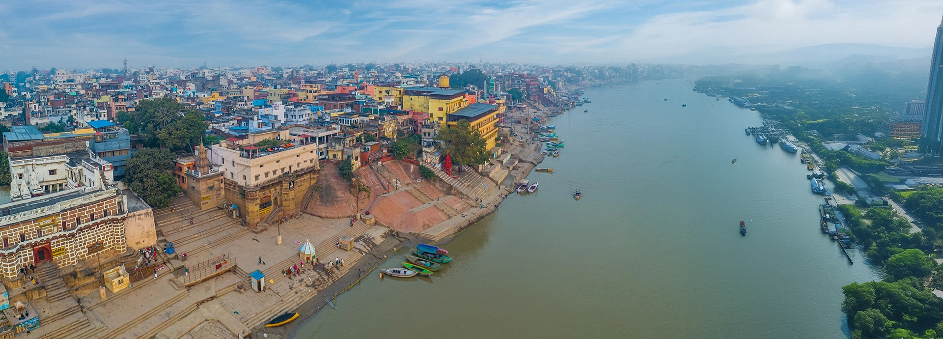 Aerial view of Varanasi’s riverside ghats and boats along the Ganges with the city sprawling into the distance.