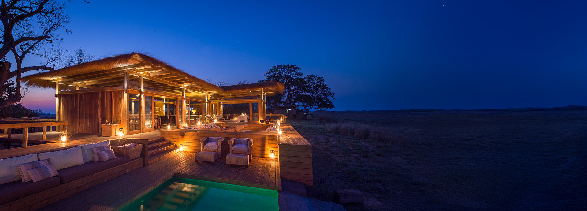 Shumba Camp’s main lounge and pool area glowing warmly at twilight