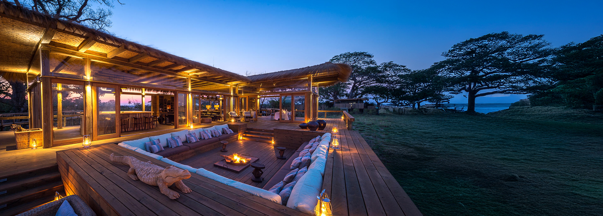 Cosy fire pit lounge surrounded by timber decking and soft lighting at Shumba Camp