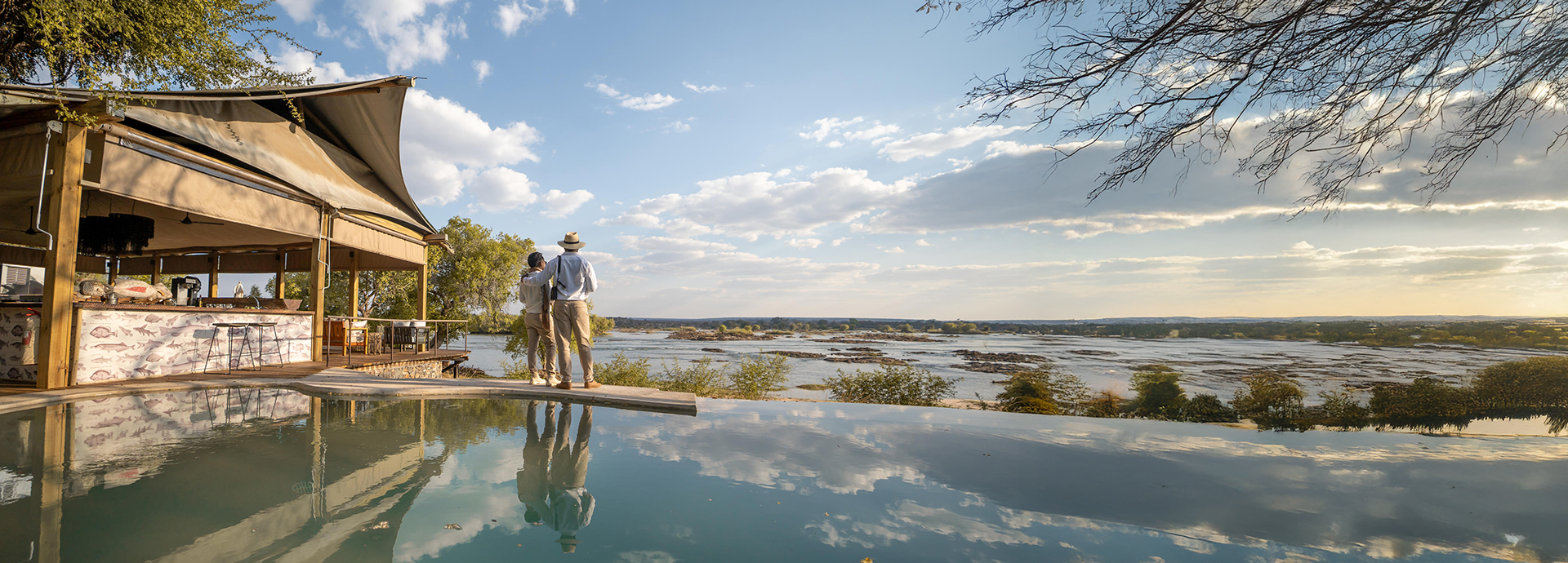 Couple enjoying the river view from the infinity pool at Toka Leya’s main deck