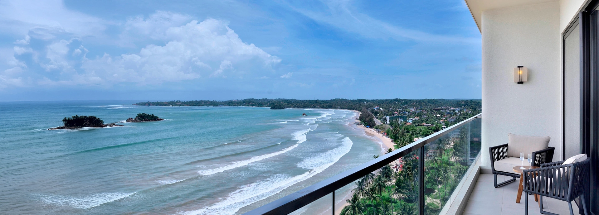A private balcony at Weligama Bay Marriott Resort & Spa with sweeping views of the Indian Ocean and the curving shoreline.