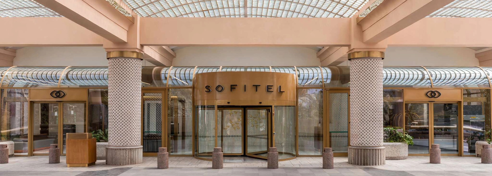 The Sofitel Cairo Nile Hotel’s grand revolving entrance sits beneath a glass canopy with elegant pillars and soft golden detailing.