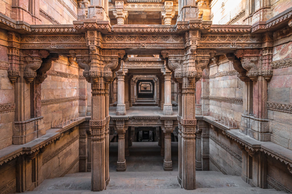 Ornately carved sandstone pillars and multiple levels inside Adalaj Stepwell, Ahmedabad