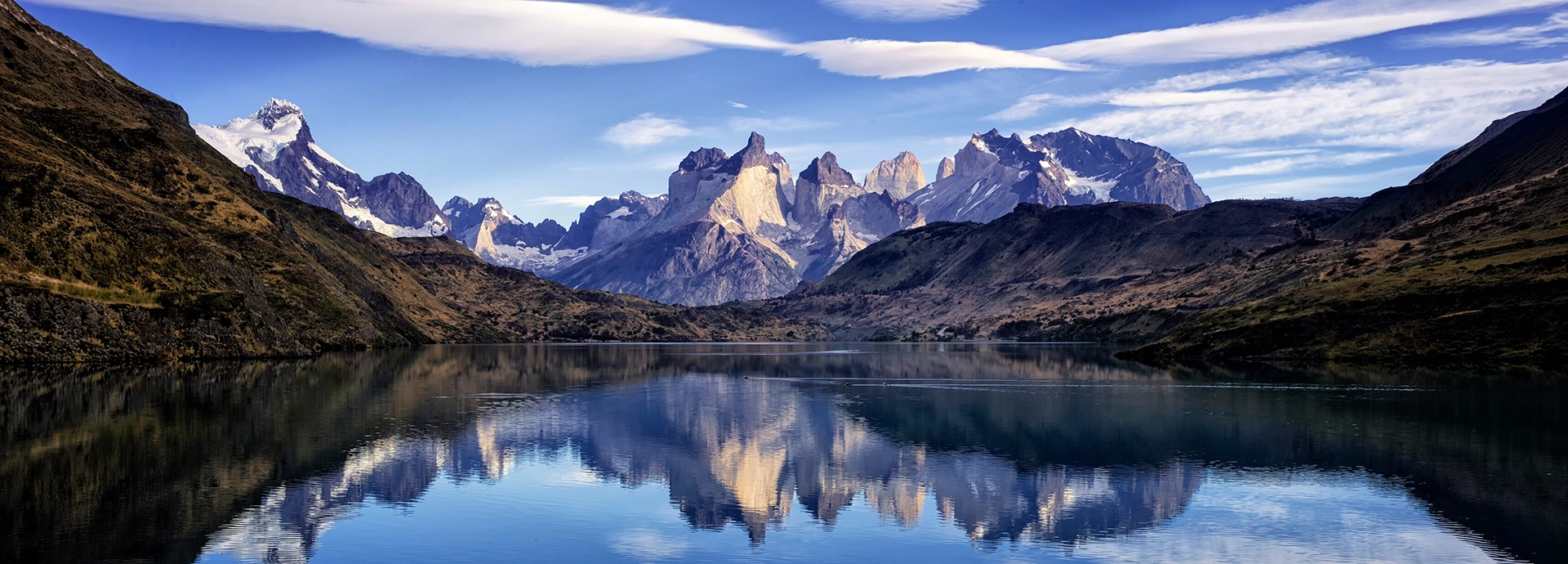 The granite towers of Torres del Paine reflected in a still Patagonian lake beneath sweeping southern skies in Chile.