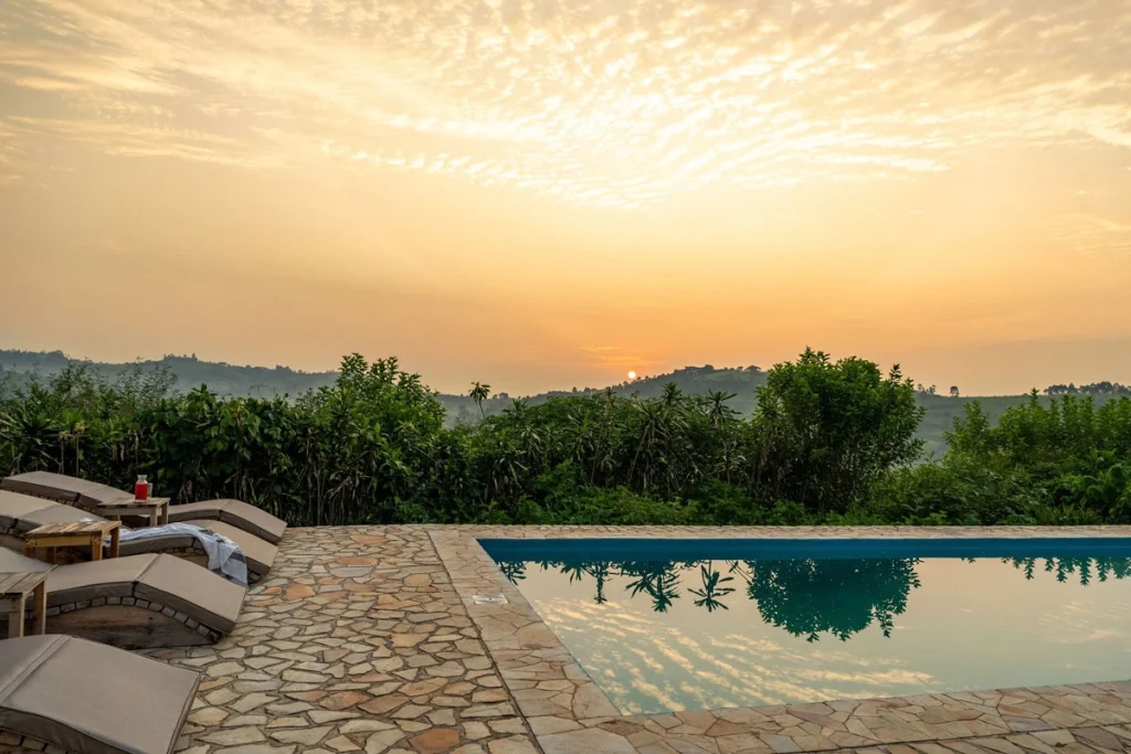 Sunset over the swimming pool at Kibale Lodge, Uganda, with loungers overlooking the hills of the western Rift Valley