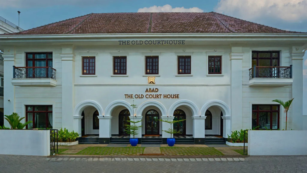 Daytime view of the heritage facade of The Old Court House, with arched entryways, dark-framed windows and a tiled roof.