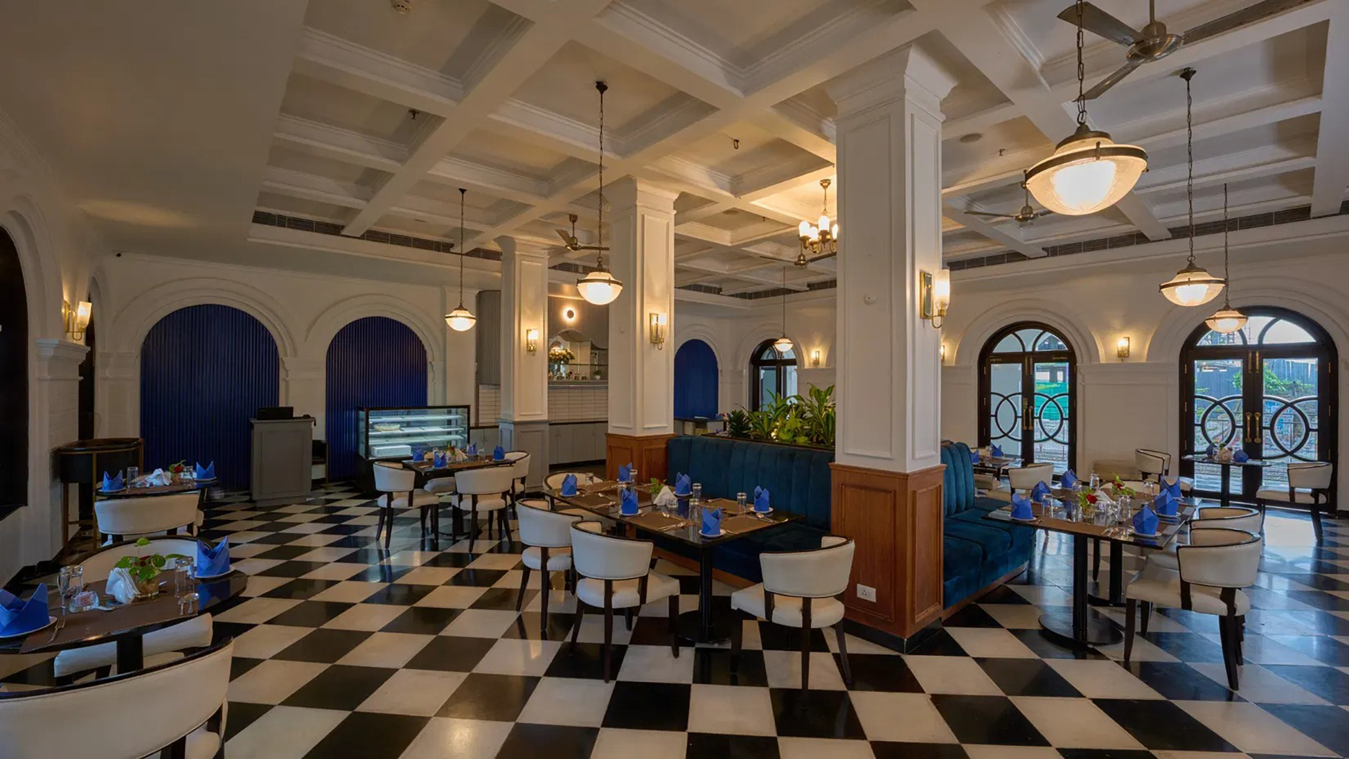 Cafe Rendezvous dining room featuring navy curtains, white columns and neatly set tables ready for guests.