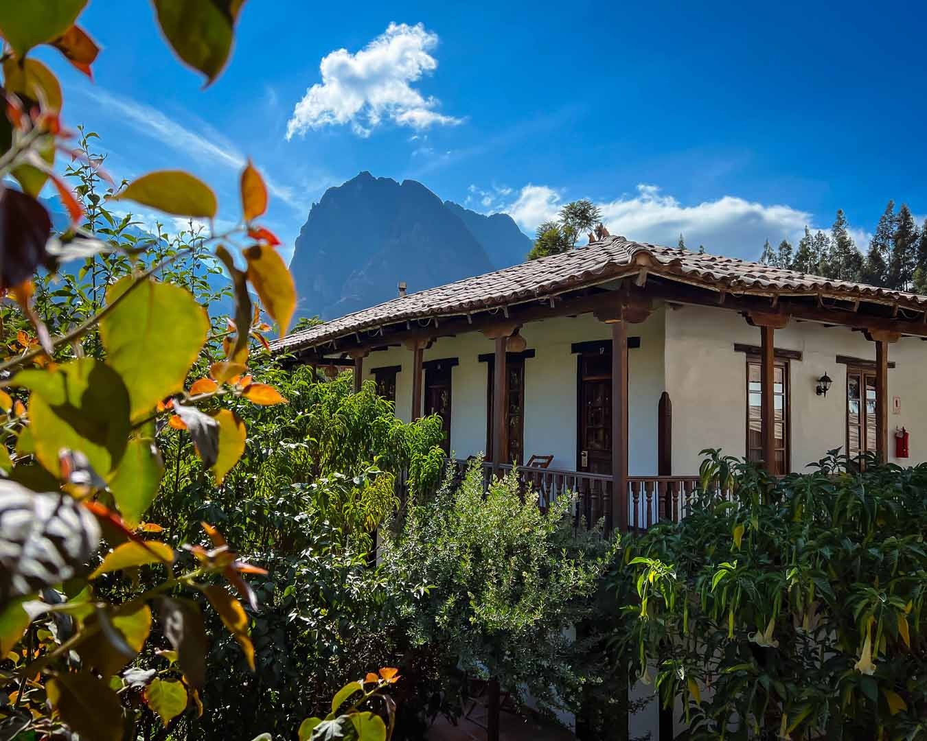 Adobe hotel building with tiled roof and timber balcony set against the peaks of the Sacred Valley