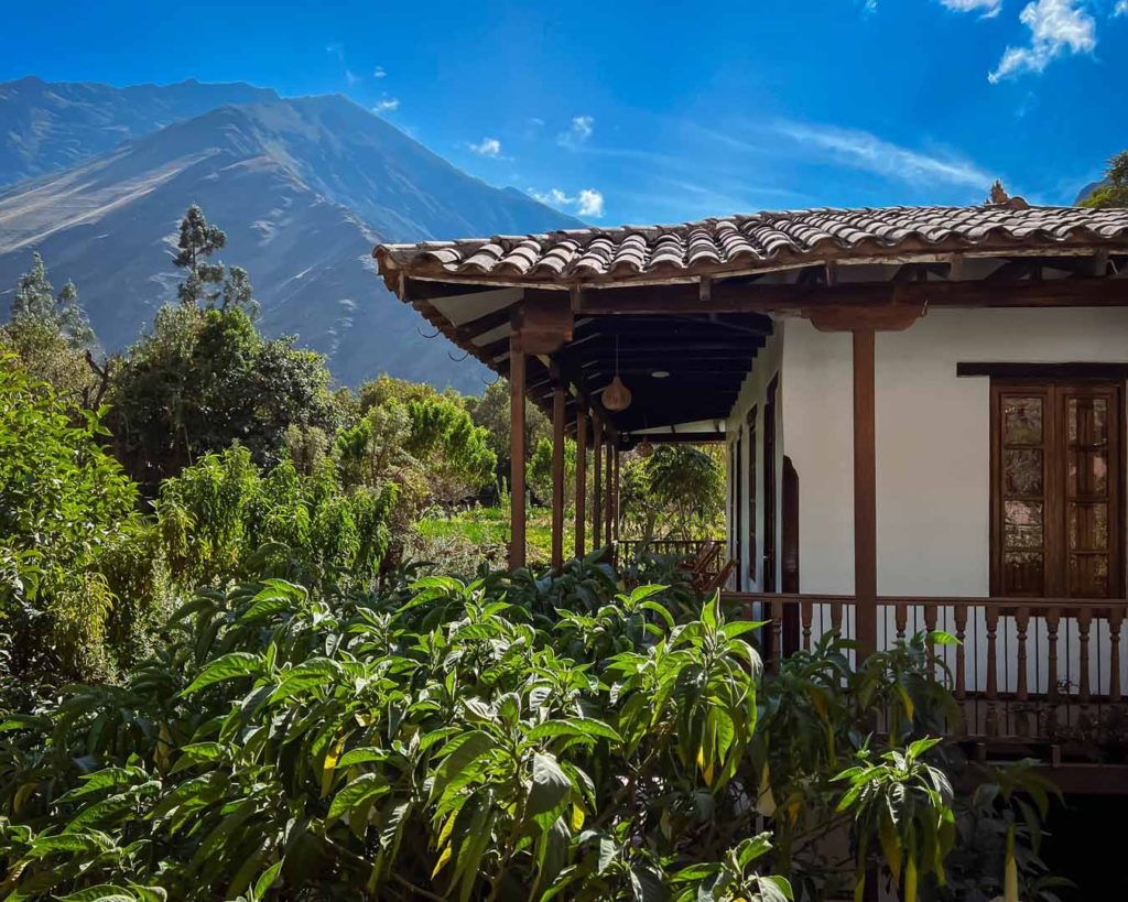 Covered terrace with timber columns overlooking gardens and the mountains of the Sacred Valley