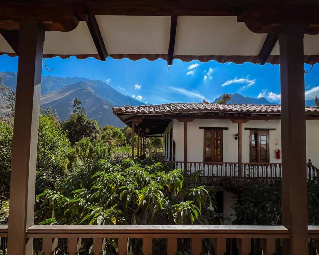 View through a wooden veranda towards the adobe hotel building and surrounding Andean peaks