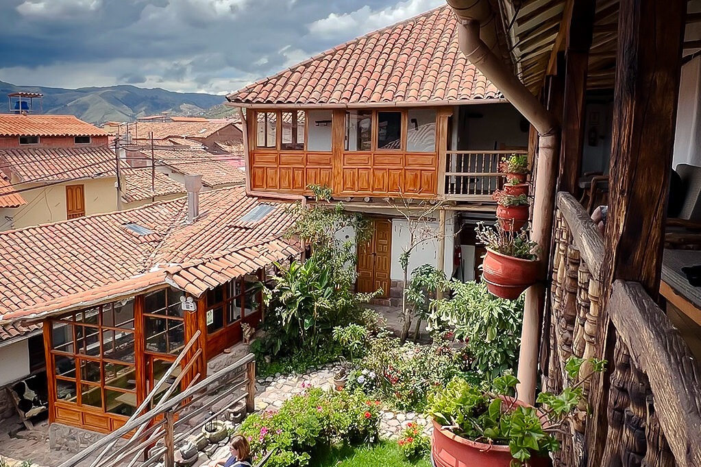 Terracotta rooftops and a wooden balcony overlooking a courtyard garden in Ollantaytambo