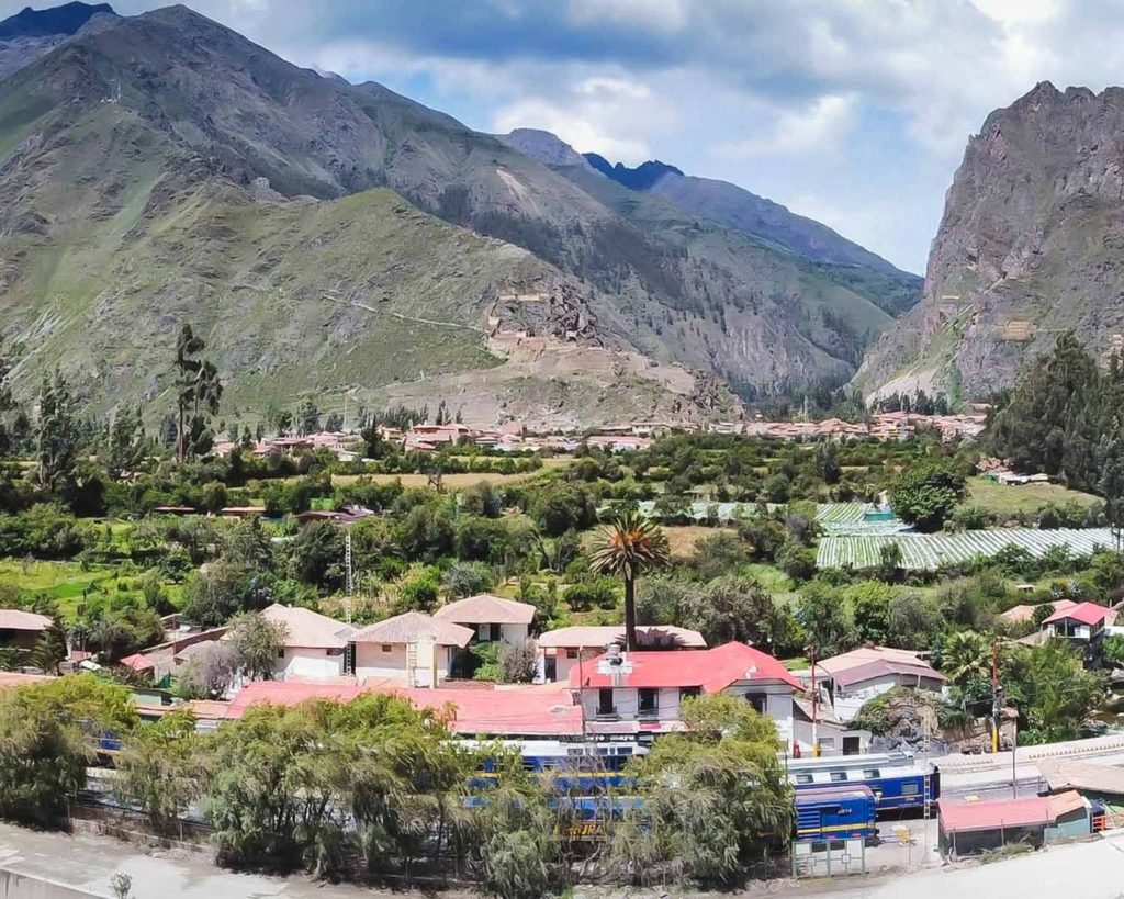 Aerial view over Ollantaytambo village and train station, framed by the Sacred Valley's mountains