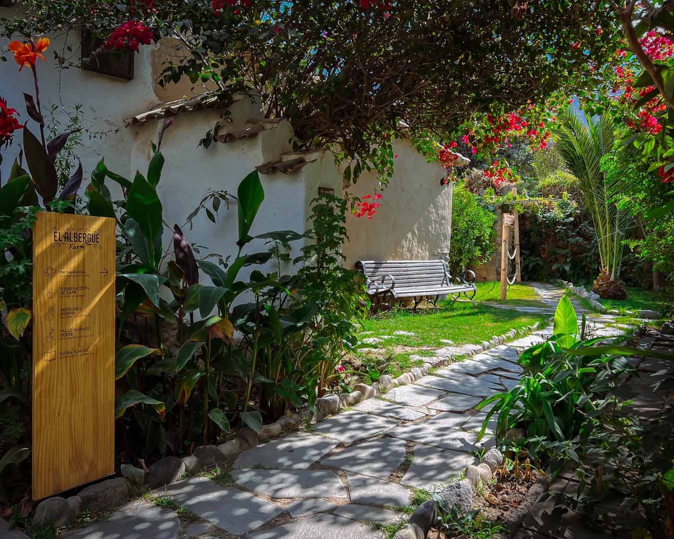 Stone pathway through the farm garden past a signpost for the Pachamanca, coffee roastery and distillery