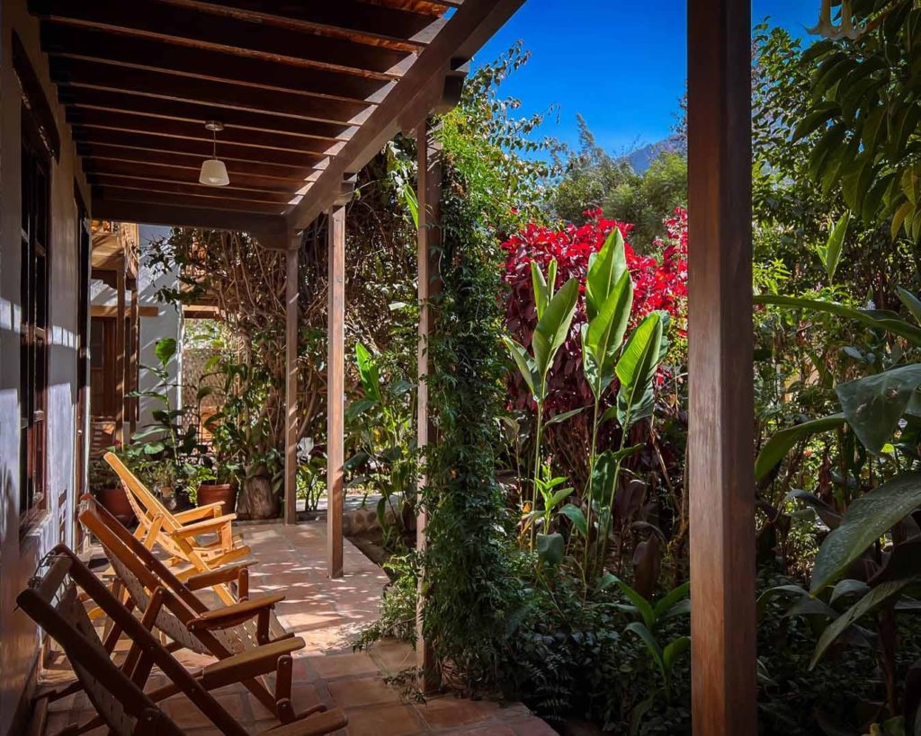 Shaded veranda with wooden loungers overlooking a garden of bright red flowering shrubs