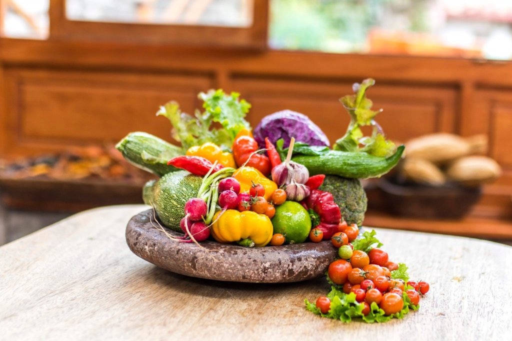 Wooden bowl piled with freshly harvested vegetables from the on-site organic farm