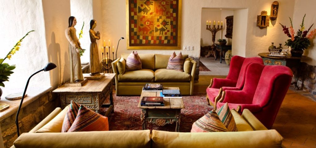 Sitting room with wooden santos figures, a kilim-patterned throw pillow display and crimson wingback chairs
