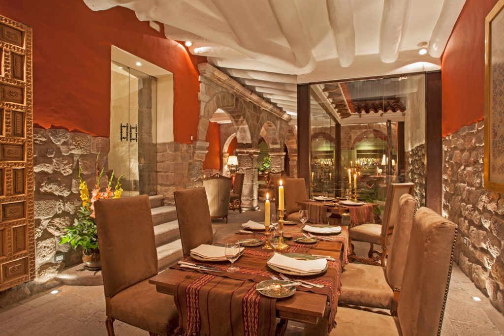 Candlelit dining room with stone archways, terracotta walls and tables dressed in striped Andean runners