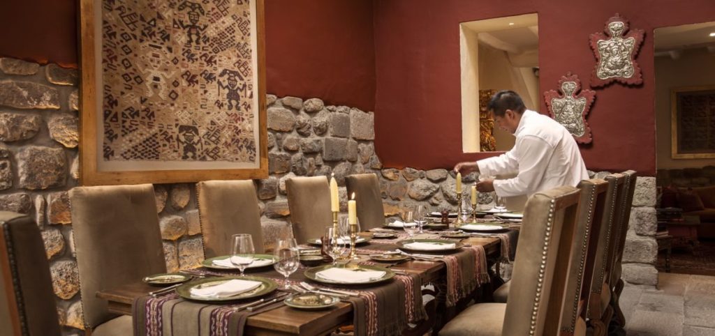 Candlelit dining room with a framed Andean textile, stone walls and a table set for a private dinner