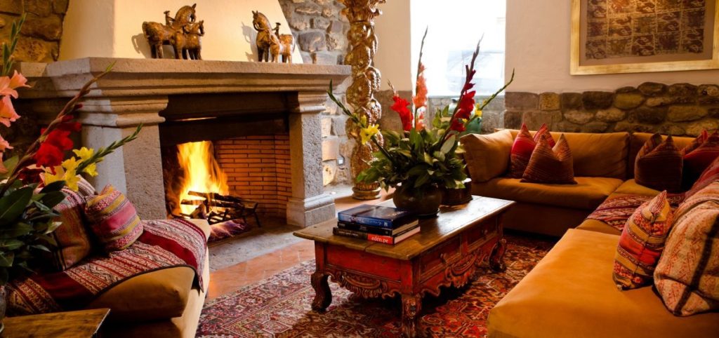 Lounge with a lit stone fireplace, bronze horse figurines on the mantel and deep sofas dressed in Andean cushions