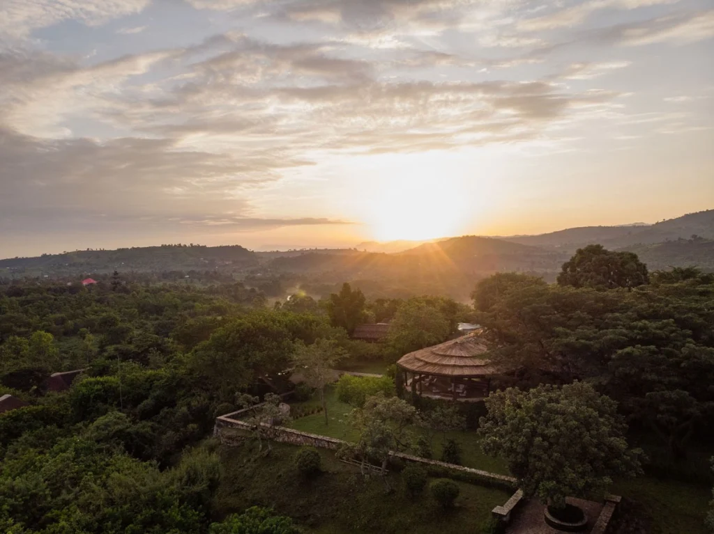 Aerial view of Kyambura Gorge Lodge at sunrise, its thatched main building set among trees above the western Rift Valley, Uganda