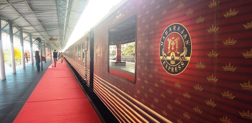 The Maharajas’ Express luxury train standing at a station platform, its opulent maroon carriage symbolising rail journeys through royal India. 