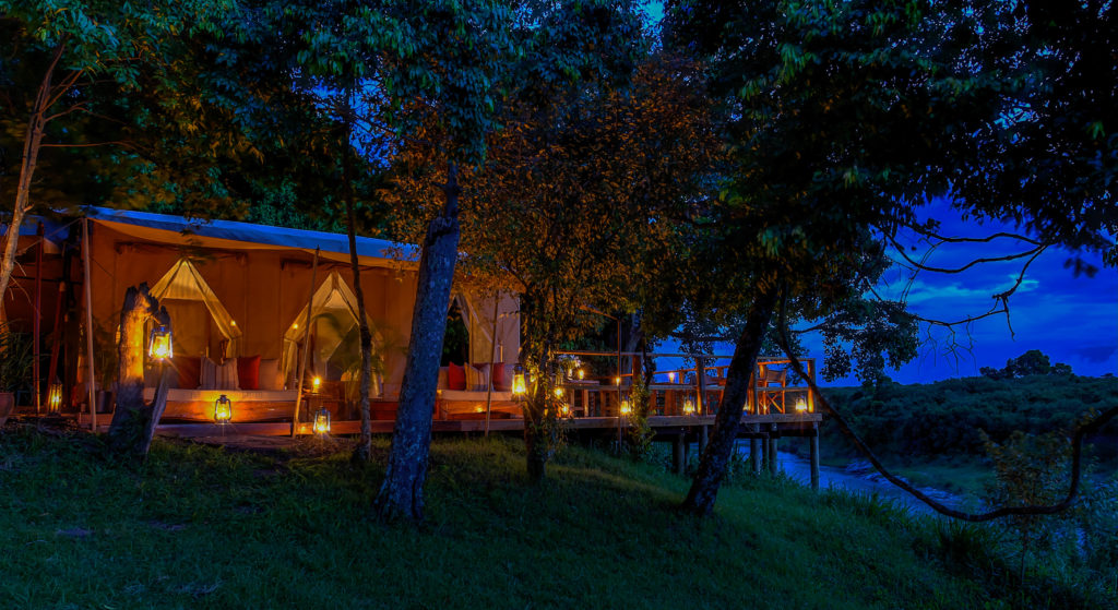 Naibor's riverside deck is strung with lit lanterns at dusk, its cushioned seating and dining tables overlooking the Talek River below.