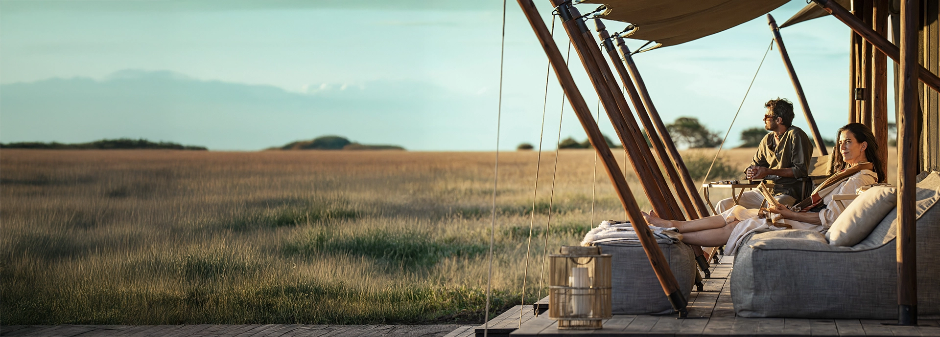 Guests recline on a shaded tented deck at Mila Tented Camp, enjoying quiet moments and sweeping views across the open plains of the Western Serengeti.