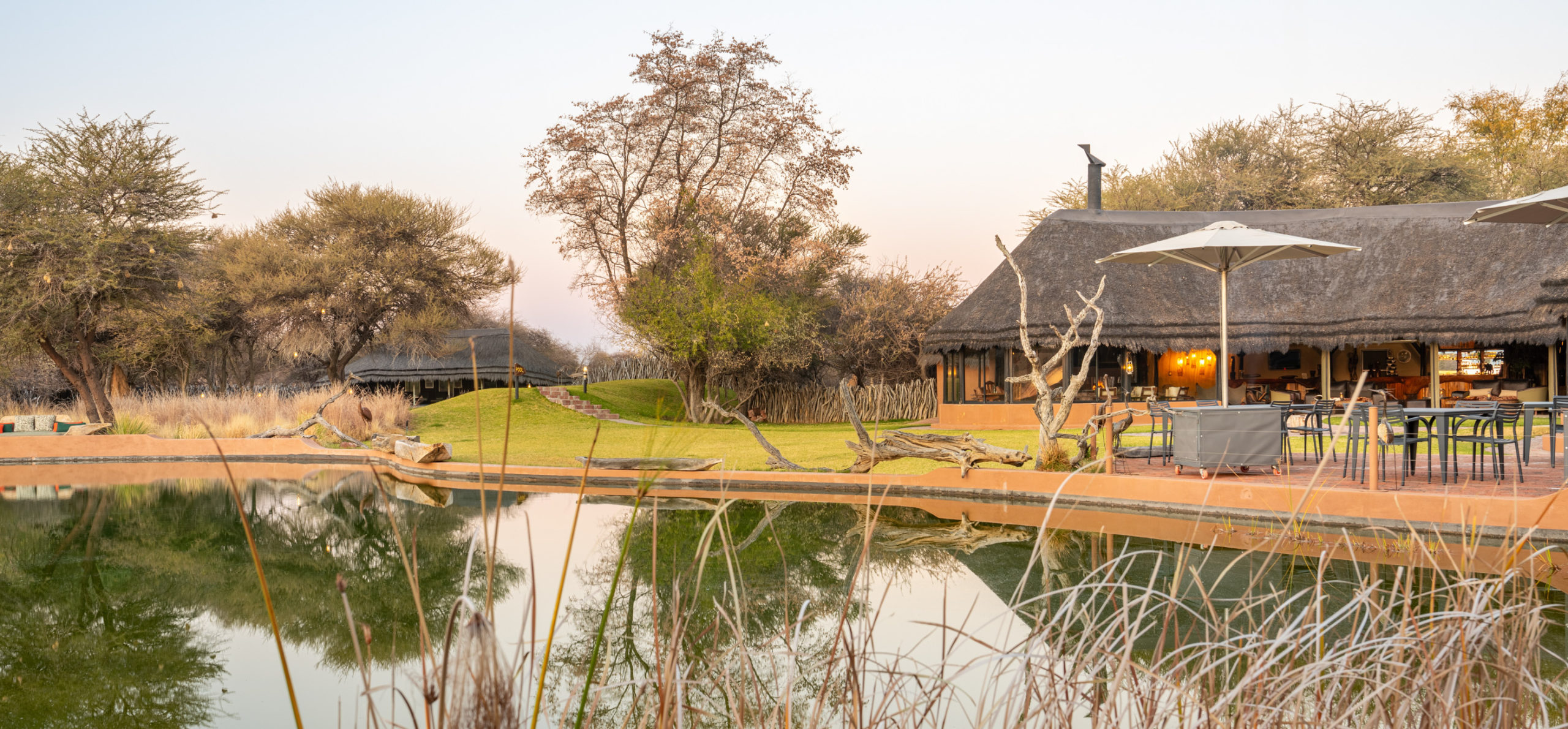 Okonjima Luxury Bush Camp at dusk with the lapa reflected in the waterhole