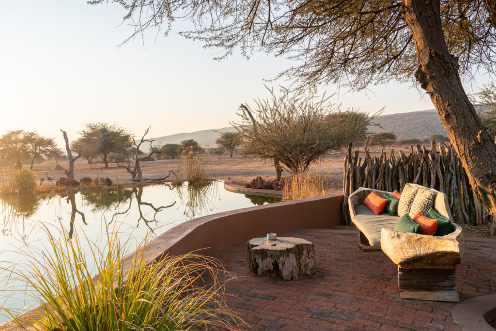 Waterhole-side lounge seating at Okonjima Luxury Bush Camp at sunset