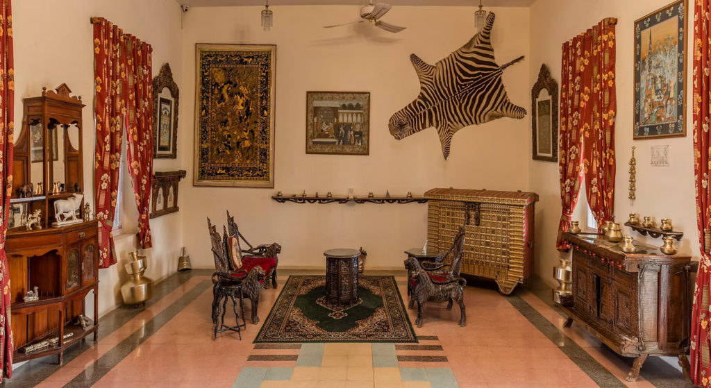 A Kathiawadi-style sitting room at Orchard Palace, Gondal, with carved lion chairs, tapestries and a mounted zebra hide