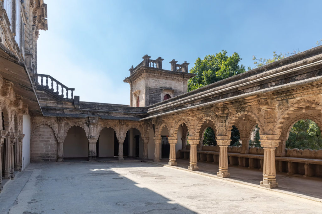 A carved stone courtyard with a corner turret and colonnaded veranda at the historic Gondal palace complex